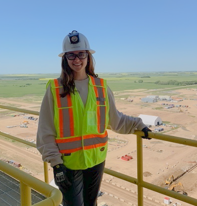 student outdoors in construction gear standing next to railing